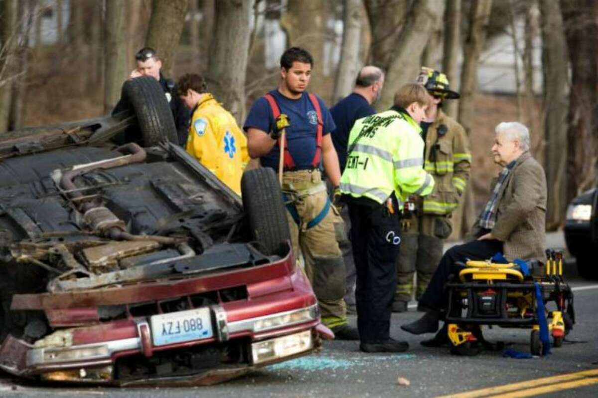 Darien EMT Dan Connell, second from right, talks with the driver of a car (right) involved in a roll-over on West Avenue in Darien near the Stamford border on March 5, 2010. One car was involved in the accident when the driver hit a tree after a sharp turn on West Avenue, traveled up an embankment and rolled the car. The driver only sustained minor injuries.