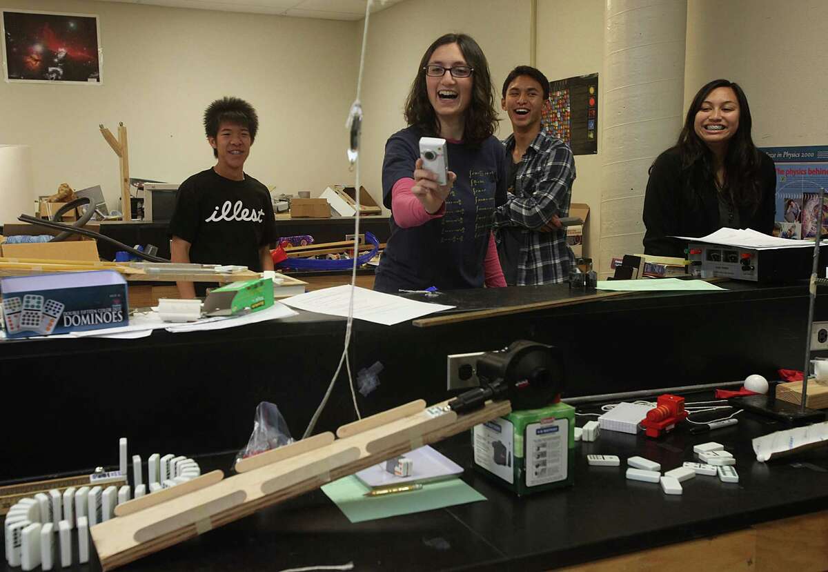 Tamar Sperlo (middle), 25 years old, takes video of her students' Rube goldberg machine in action as they show their final class project in physics at Westmoor High School in Daly City, Calif., on Friday, May 28, 2010. At far left is sophomore Henry Cheung, 16 years old, Ryan Reyes (middle), 17 years old junior, and Jamielyn Williams (right), 16 year old junior.