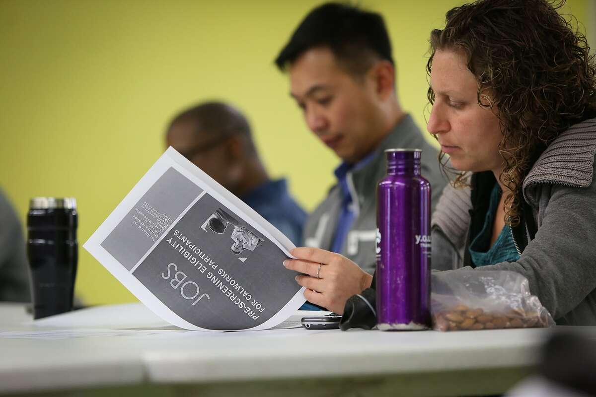 Amanda Sommers and Wilson Ho Yin Cheh review a packet from Jobs Now, a program by Human Services Agency, helps businesses and job seekers connect and fulfill employment opportunities in San Francisco on Wednesday, May 13, 2015.