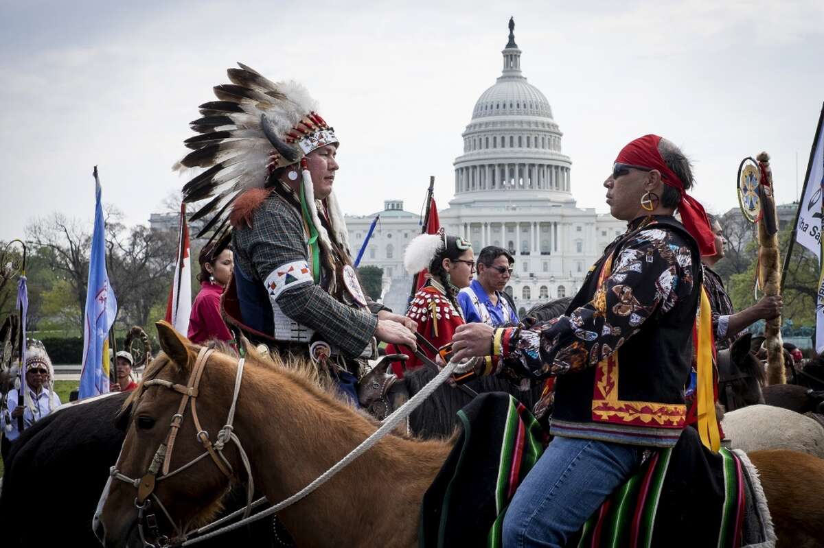 Members of the Cowboy and Indian Alliance (CIA), a group of ranchers, farmers and indigenous leaders, ride horses past the U.S. Capitol during a protest against the Keystone XL pipeline on the National Mall in Washington, D.C., U.S., on Tuesday, April 22, 2014. TransCanada Corp. is awaiting a U.S. permit to build the northern leg of Keystone XL, which would supply U.S. Gulf Coast refineries with crude from Alberta's oil sands. Because it crosses an international boundary, the proposal requires State Department approval. Photographer: Pete Marovich/Bloomberg