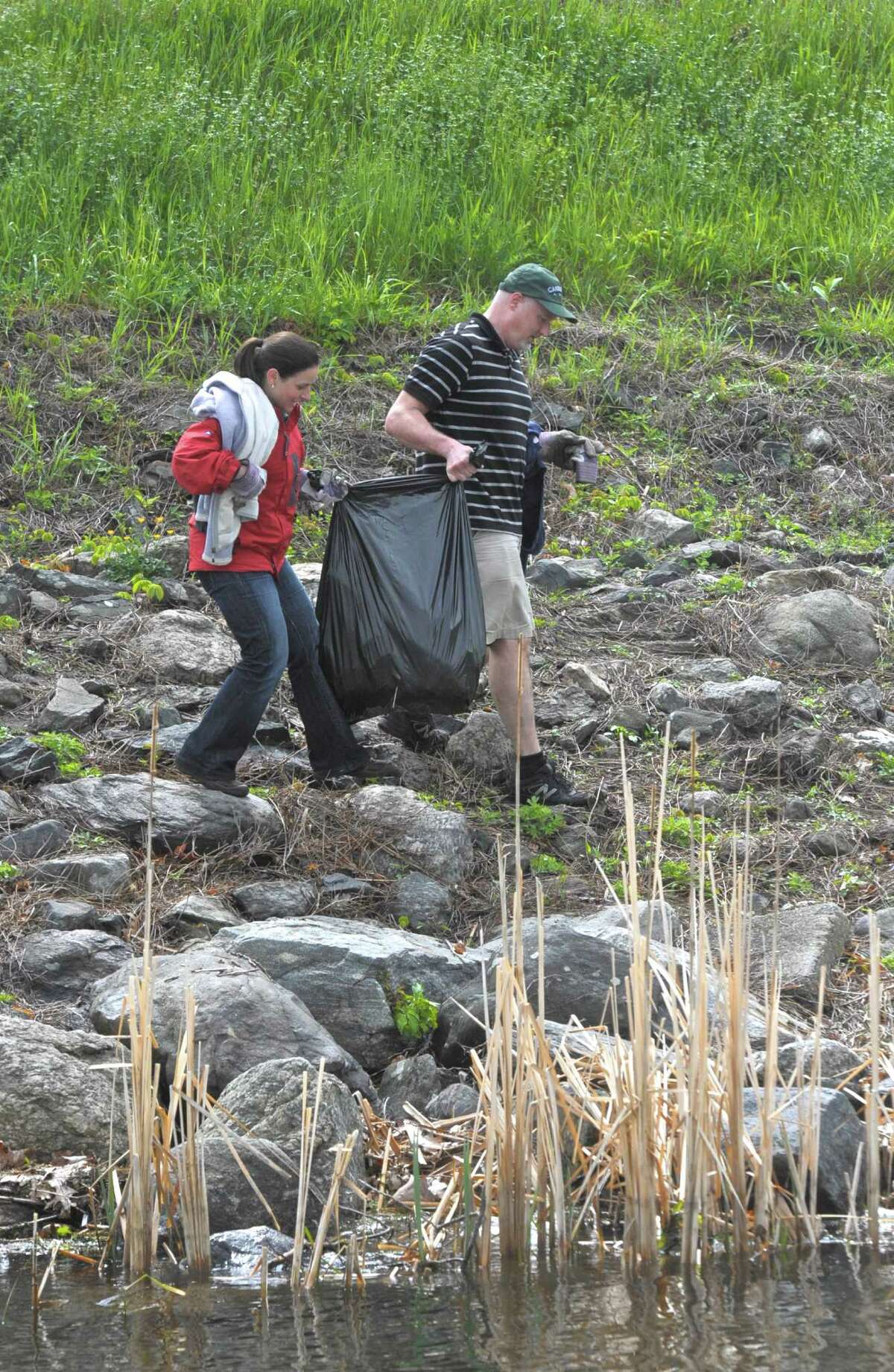 Nicole Gurney, a teacher with Project CLEAR, and Philip Pacchiana, of Danbury, carry a bag full of trash along the shore near Danbury Town Park during the 15th Annual John Marsicano Memorial Lake Cleanup, on Saturday, May 16, 2015, in Danbury, Conn, on Candlewood Lake.