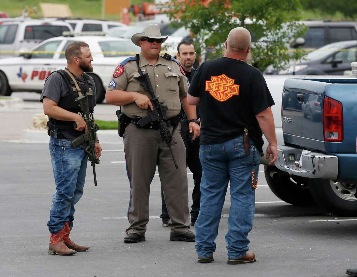 Law enforcement officers talk to a man near the parking lot of a Twin Peaks Restaurant Sunday, May 17, 2015, in Waco, Texas, after a shooting involving rival biker gangs. Waco police Sgt. W. Patrick Swanton told KWTX-TV there were “multiple victims” after gunfire erupted between the gang members. (Rod Aydelotte/Waco Tribune Herald via AP)