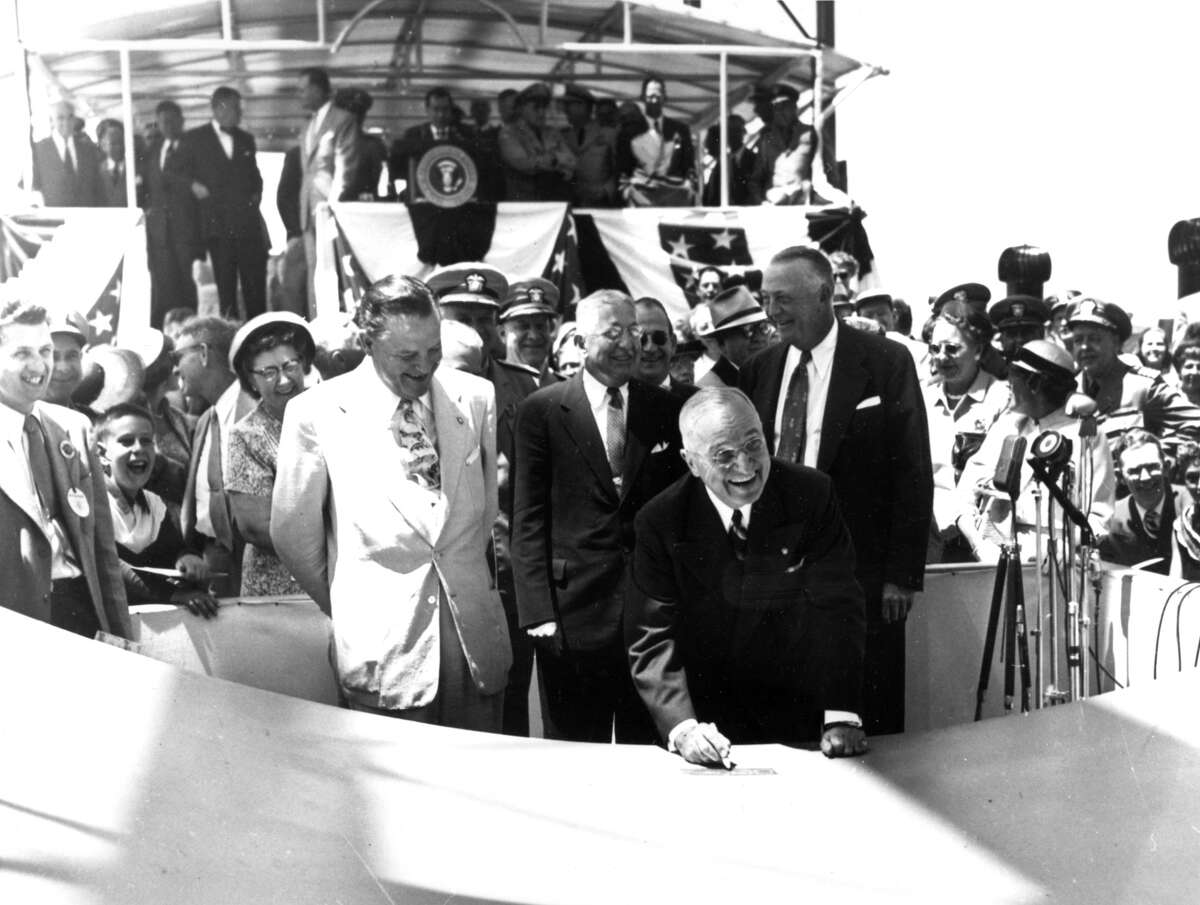 President Harry S. Truman smiles as he signs his initials to the keel plate of the USS Nautilus, the first atomic-powered submarine in history, during a ceremony at Groton, Conn., on June 14, 1952.