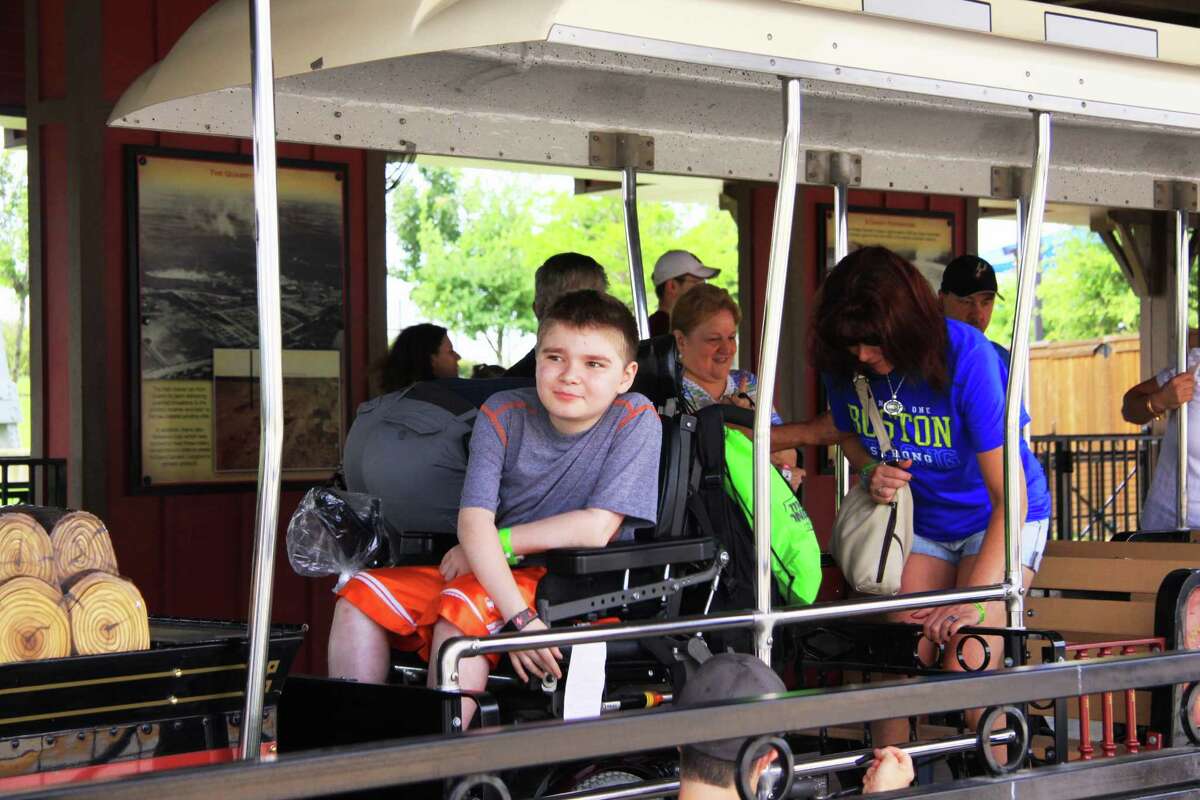 Seth Courtemanche, left, and his mother, Monique, right, get ready to take a ride on the Wonderland Express train at Morgan's Wonderland in June 2014.