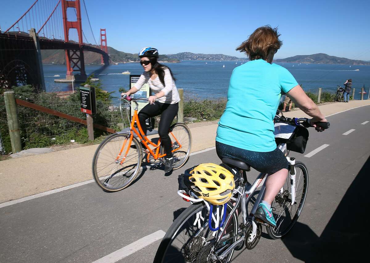 A bicycle rider rolls past the Golden Gate Bridge with her helmet strapped to the back in San Francisco, Calif. on Saturday, Feb. 14, 2015. A bill has been introduced in the state legislature that would make helmets mandatory for all bicycle riders, requiring adults to wear them in addition to minors. **MANDATORY CREDIT FOR PHOTOG AND SF CHRONICLE/NO SALES-MAGS OUT-TV OUT**