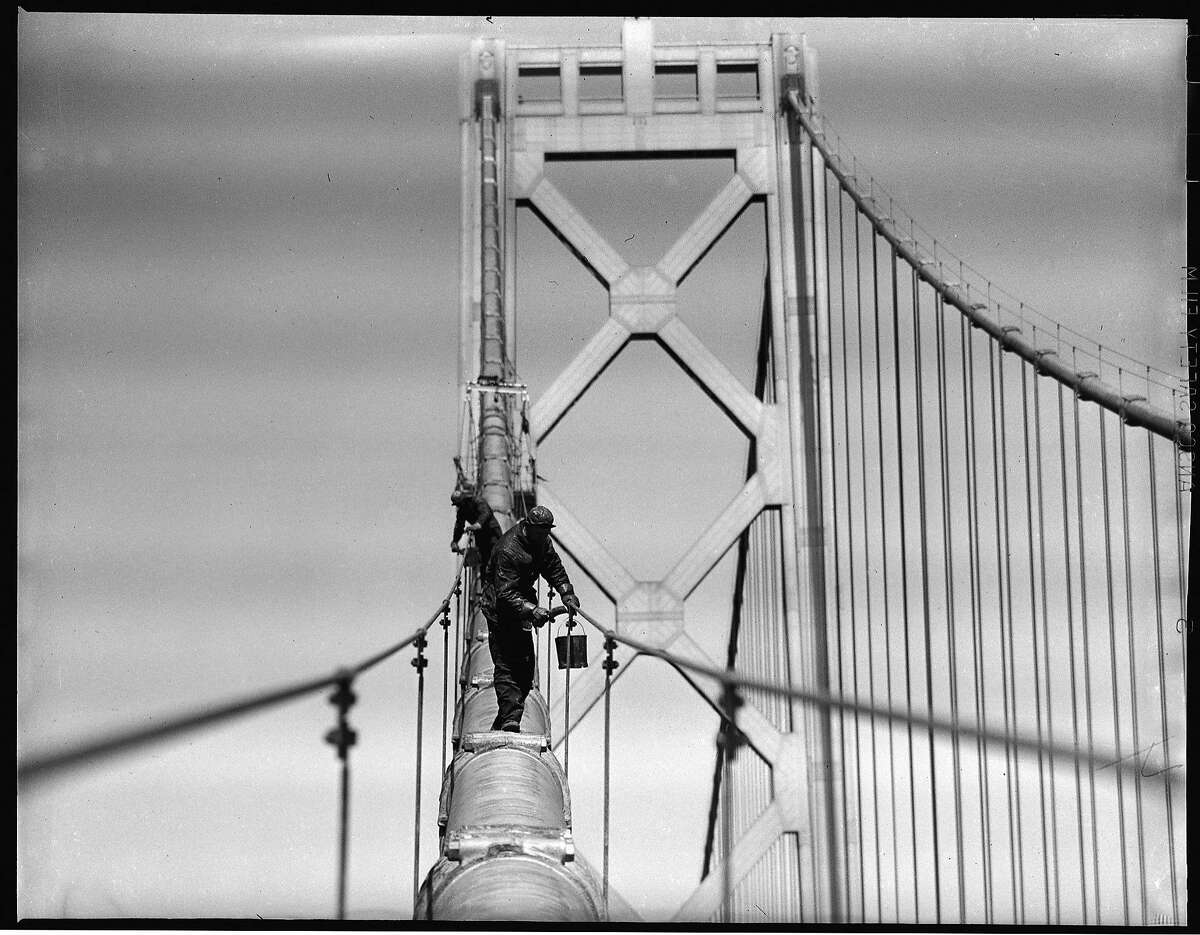 1948年:工人们粉刷海湾大桥的西跨，当时它已经建成十多年了。海湾大桥比金门大桥早建成不到一年，被富兰克林·德拉诺·罗斯福(Franklin Delano Roosevelt)宣布为美国历史上最伟大的建筑工程。这张照片是由杜克·唐尼拍摄的，他是一位长期的纪事摄影师，经常把自己放在不稳定的地方，以获得很好的结果。