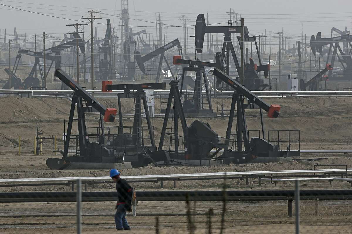 FILE - In this January 2015 file photo, a person walks past pump jacks operating at the Kern River Oil Field in Bakersfield, Calif. California regulators on Monday expanded their list of thousands of state-permitted oil and gas wells where below-ground injections may be contaminating drinking-water reserves. (AP Photo/Jae C. Hong, File)