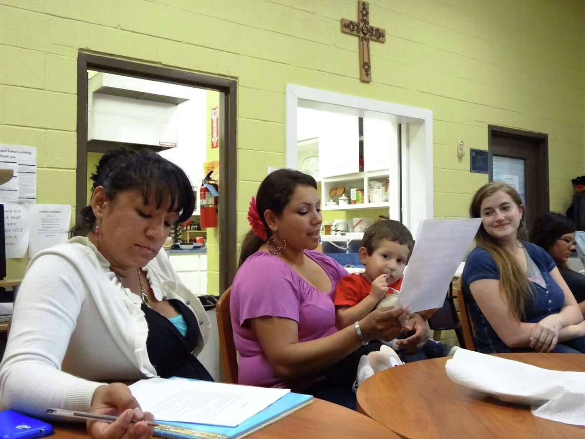 Veronica Colunga holds her son Leonardo while reading her original children's story at the Guadalupe Home as part of a Gemini Ink Writers in Communities workshop. Jessica Perez (left) and Elya Surface (right) listen and offer support.