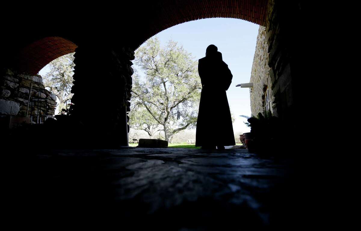 Father Rommell Perez looks out from an arcaded corridor at Mission Espada. Exterior and interior restoration to the mission, Texas' oldest, were recently completed.