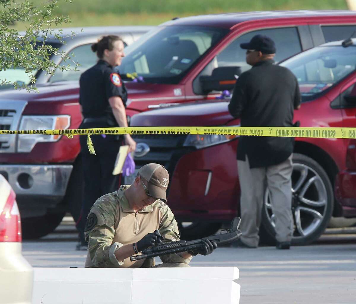 A police officer recovers a shotgun while sweeping through the parking lot of a Twin Peaks restaurant Tuesday, May, 19, 2015, in Waco, Texas. A deadly weekend shootout involving rival motorcycle gangs at the restaurant apparently began with a parking dispute and someone running over a gang member's foot, police said Tuesday. (Jerry Larson/Waco Tribune-Herald via AP)