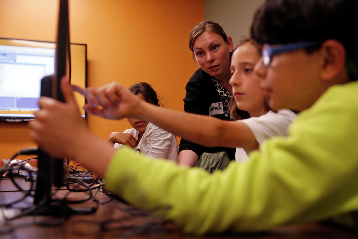 Instructor Sarah Rich helps Alex Sanchez (center), 10, and Diego Castro, 9, during a coding class.