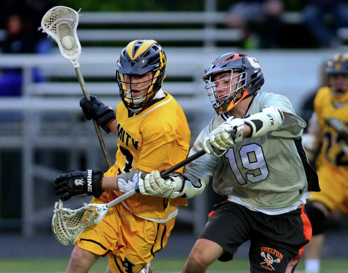 Shelton's Kyle McGinnis, right, tries to block Amity's Matt Attolino as he comes behind the goal, during boys lacrosse action in Shelton, Conn. on Thursday May 21, 2015.