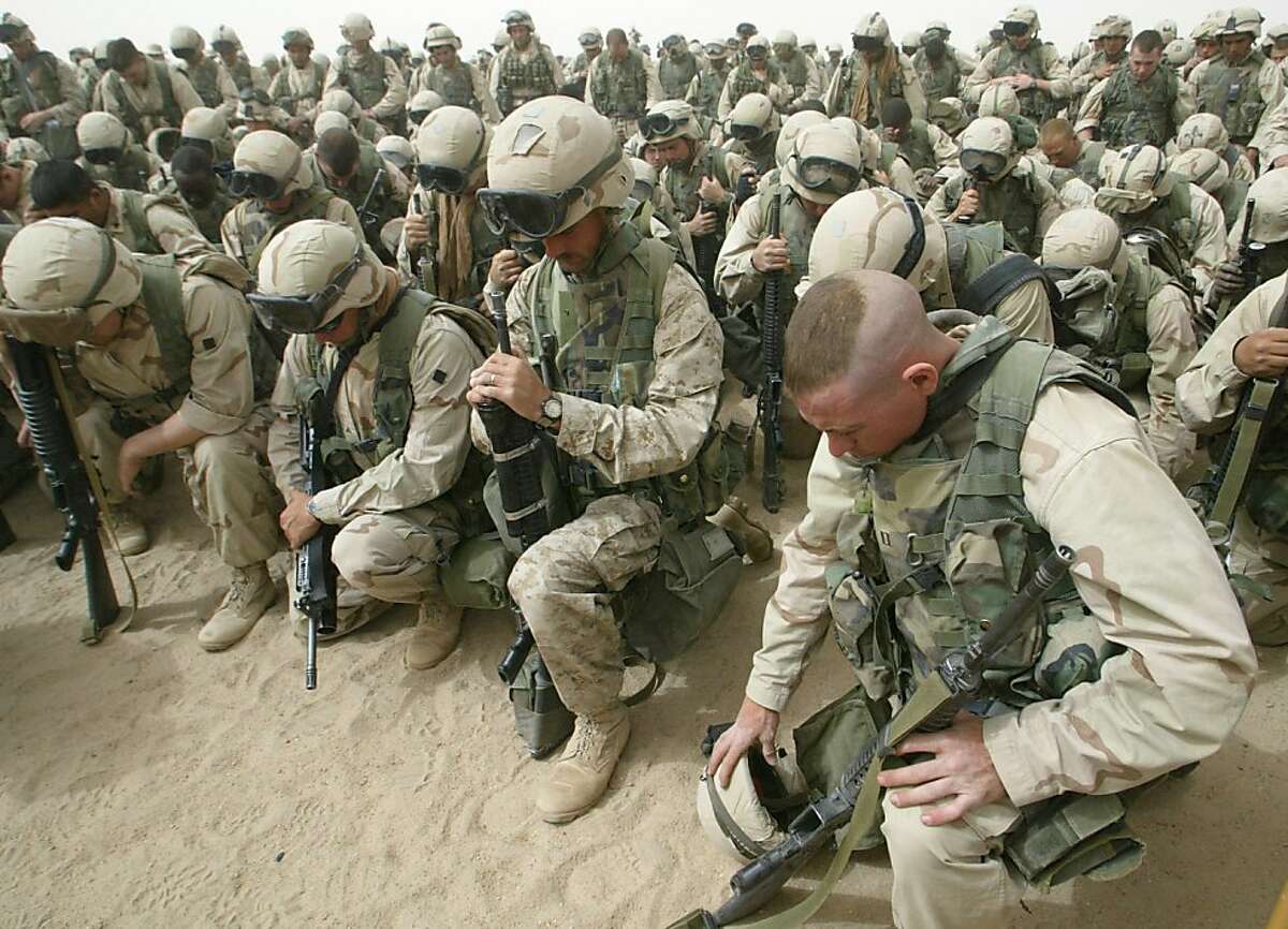 Marines kneel and pray as the 2nd Battalion, 8th Regiment prepares to leave Camp Shoup, north of Kuwait City, in a north-bound direction 20 March, 2003. More than 150,000 allied troops gathered in positions near the Iraqi border to start their advance into southern Iraq. On March 20, 2003 the United States headed a coalition with UK and other forces to invade Iraq.