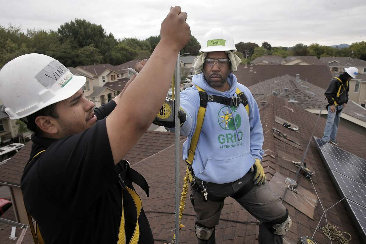 William Arreola, (left) The Rising Sun Energy Center job training program is instructed by roof supervisor, Frank Ross with Grid Alternatives, as they install solar panels on the roof of a home in Richmond, Calif., as seen on Fri. May, 22, 2015.