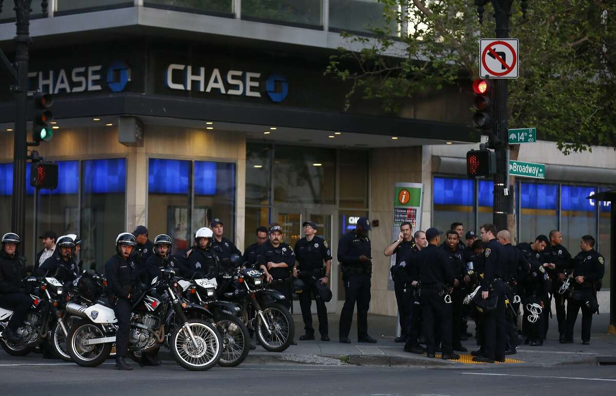 Oakland police officers watch protesters from the corner of 14th and Broadway during a rally and march called for by the Black Youth Project to protest the "stealing of black women's lives by state sponsored violence" May 23, 2015 in Oakland, Calif.