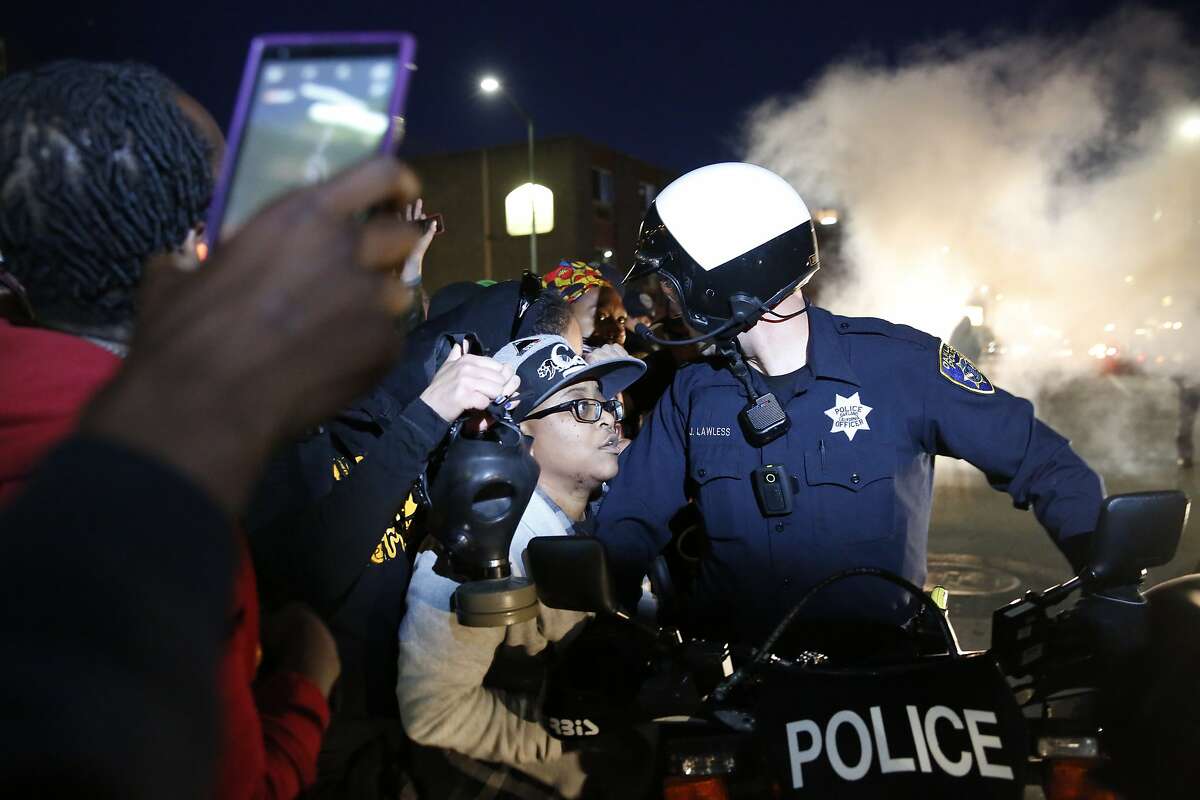 A flash bang grenade goes off as protesters push against Oakland police as they attempt to continue marching past 3rd and Washington during a rally and march called for by the Black Youth Project to protest the "stealing of black women's lives by state sponsored violence" May 23, 2015 in Oakland, Calif.