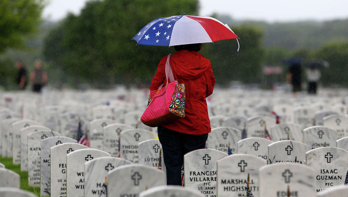 Janie Ramos tvisits her father's grave after the Memorial Day ceremony Monday May 25, 2015 at Fort Sam Houston National Cemetery. Her father, Joe J. Ramos, served in the Army during World War II.