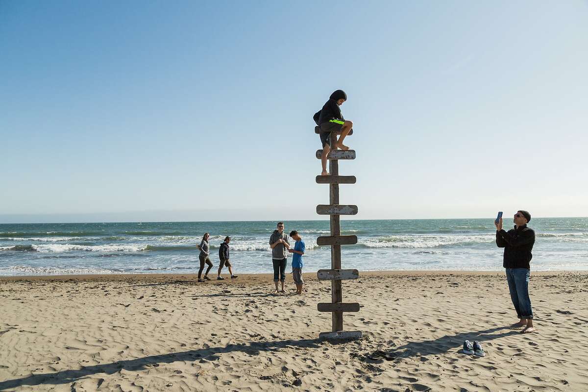 Chet Weiner, right, takes a photo of his son Laish Doris-Weiner, 9, as he climbs atop a wood ladder in the sand in Stinson Beach, Calif., Saturday, May 23, 2015.