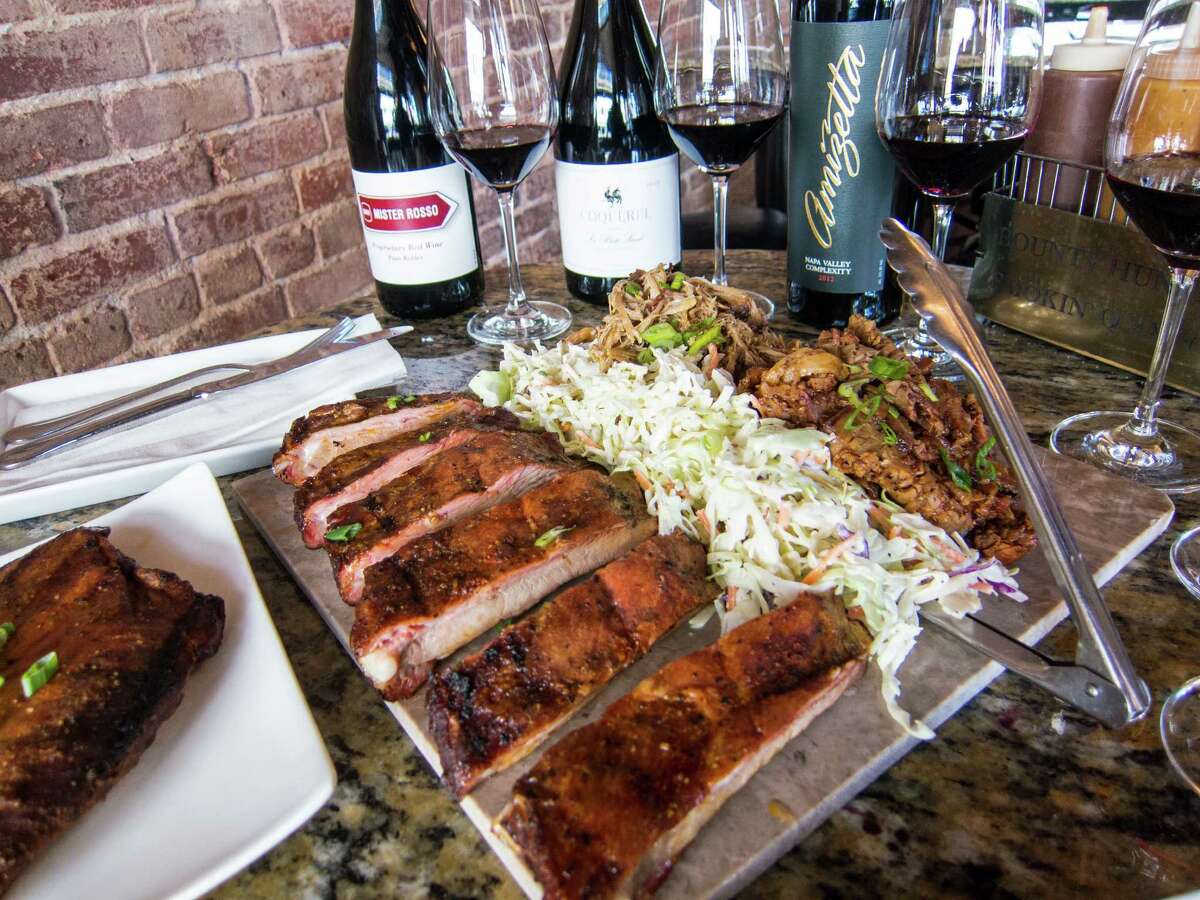A table filled with a flight of wine pairings as well as brisket, pork ribs and pulled pork at the Bounty Hunter Wine Bar & Smokinâ BBQ in Napa, Calif.