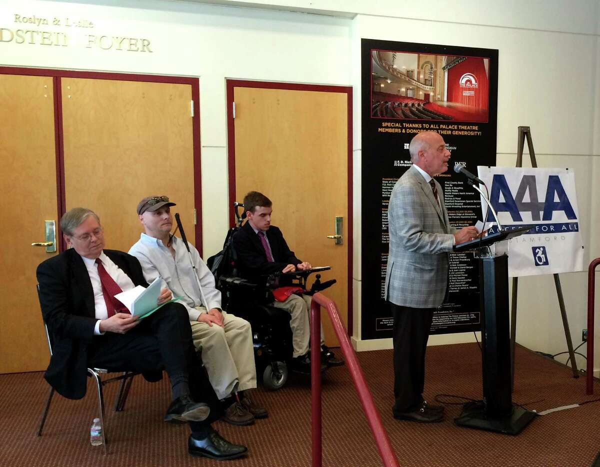 Frank Mercede, chairman of the Stamford Access 4 All Committee, gives remarks Wednesday, may 27, 2015 at the Palace Theater in Stamford, Conn. Seated, from left: Mayor David Martin, committee member Phil Magalnik and Andrew Burbank.