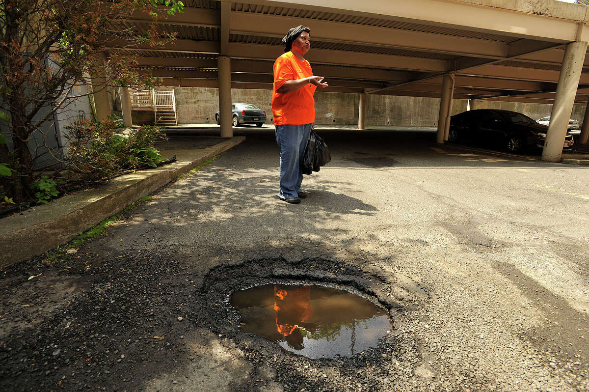 Trinity Park resident Karen Wood shows one of the many potholes in the parking lot of her apartment building in Stamford, Conn., on Wednesday, May 27, 2015. Wood has lived in the building for almost 19-years.