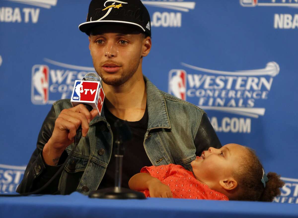 Golden State Warriors' Stephen Curry speaks to the media as his daughter Riley plays after Warriors' 104-90 win over Houston Rockets in Game 5 of NBA Playoffs' Western Conference Finals at Oracle Arena in Oakland, Calif., on Wednesday, May 27, 2015.