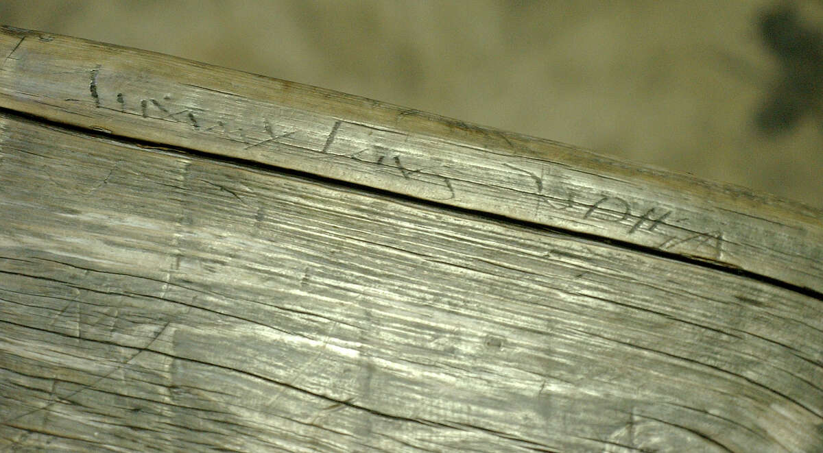 A close-up of the inscription a young Johnny Cash carved into a River Bank bench when he and his future wife Vivian Liberto were courting in 1951. Because of decades of weathering and additional carving, only a few letters are now visible, including the J in Johnny and part of Vivian's name. After becoming aware of the bench’s historical significance, city officials removed it from the River Walk, eventually giving it to the Witte Museum, where it is on permanent display.