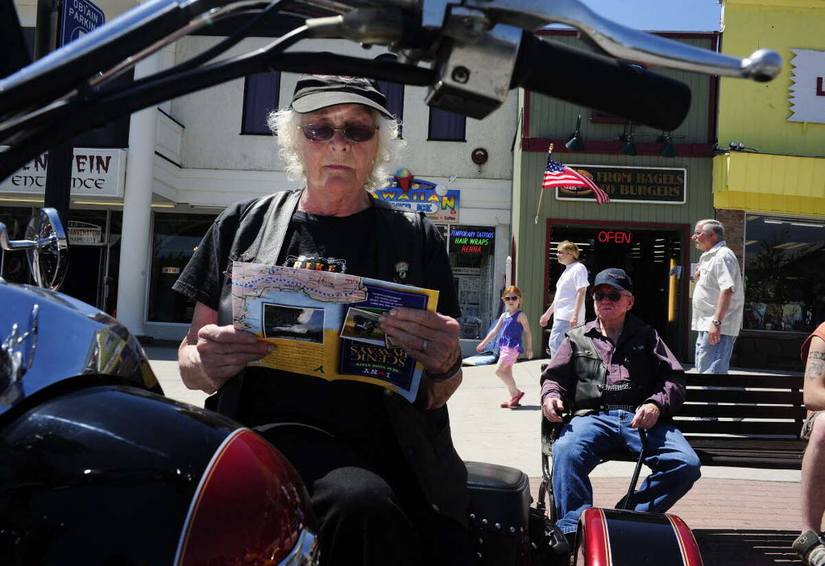 Americade riders, Jeannette Pittsley, 77, from East Freetown, MA, looks over a brochure for Lake George attractions as her husband, Louis Pittsley, 83, sits on a bench along Canada St. on Monday, June 2, 2014, in Lake George, N.Y. The two have been coming to Americade for 27 years. Americade is the worldOs largest multi-brand motorcycle touring rally.