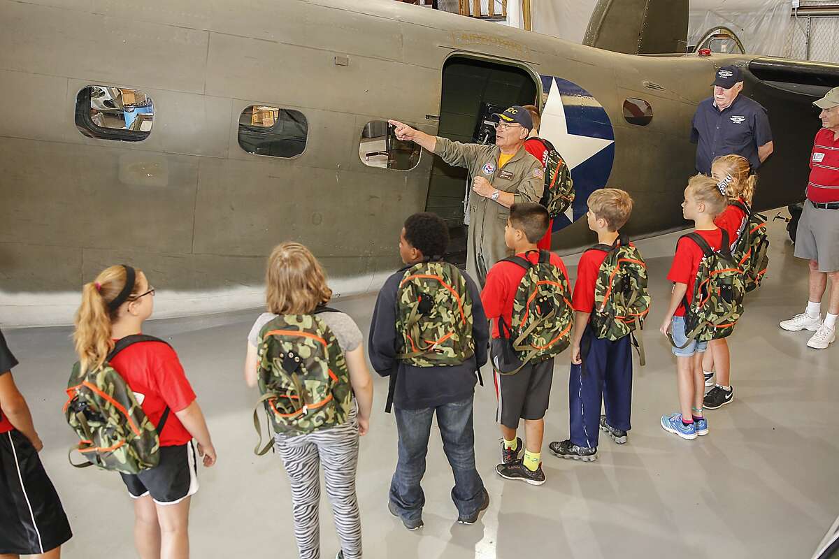 Frank Vargas who is a pilot for Wings over Houston, talks with students from Katy Elementary about WWII planes and jumping out of a plane with a parachute at the Commemorative Air Force's Hanger located at West Houston Airport on May 22, 2015.