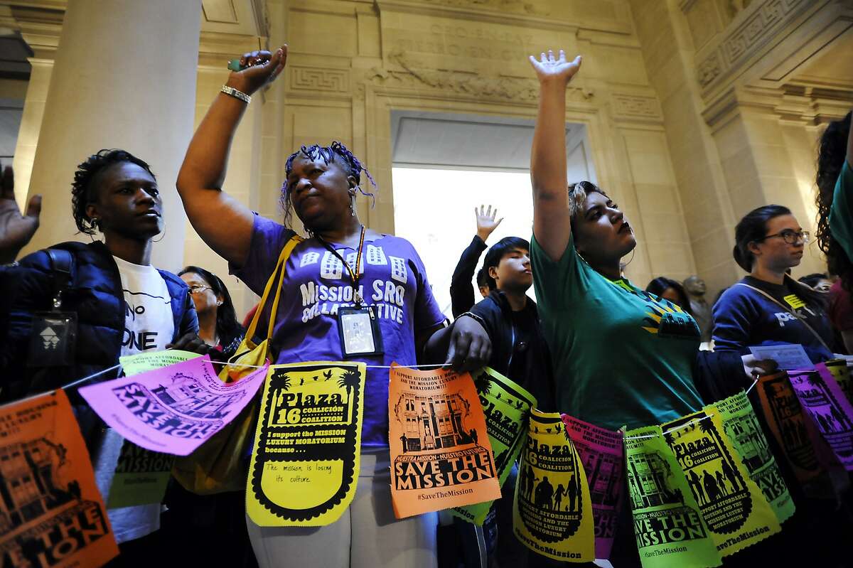 Activists and protestors raise their hands as they hold a prayer circle in front of the mayors office as a board of supervisors meeting takes place where supervisor David Campos was expected to introduced a bill placing a temporary moratorium on the construction of new market-rate residential developments, at City Hall in San Francisco, CA Tuesday, June 2, 2015.