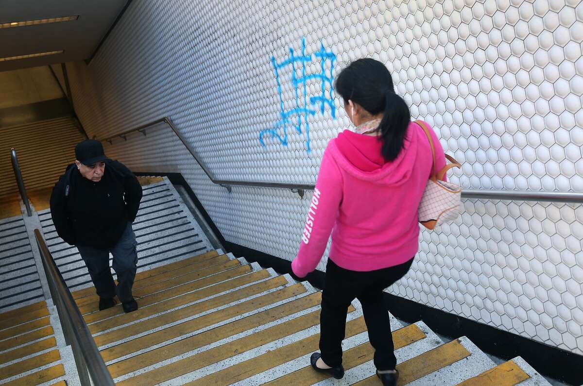 Commuters walk past graffiti sprayed on a stairwell at the Powell Street BART station in San Francisco, Calif. on Wednesday, June 3, 2015.