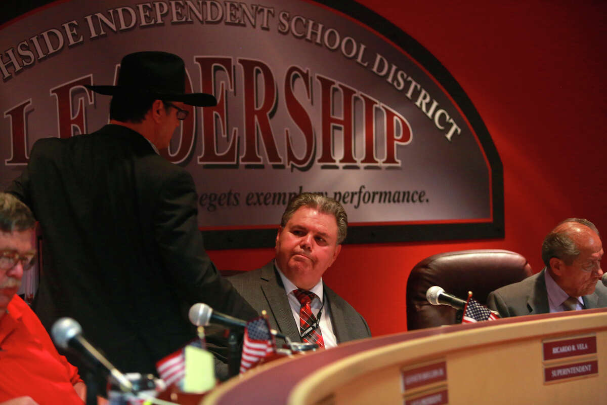 Southside Independent School District trustee Loren Brewer shakes the hand of Superintendent Ricardo Vela (seated) after the board voted to place Vela on indefinite leave.