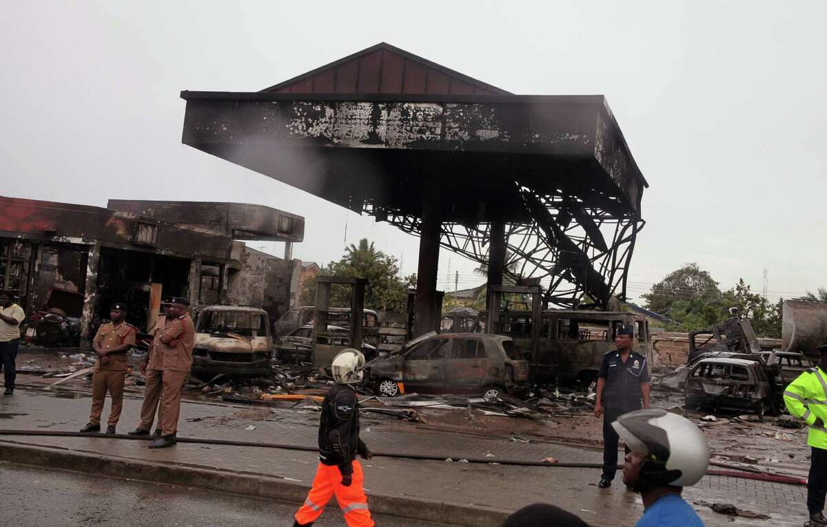 Ghana security personnel stand near the gas station that exploded in Accra, Ghana, Thursday, June 4, 2015. Flooding in Ghana's capital swept stored fuel into a nearby fire, setting off a huge explosion at a gas station that killed scores of people and set alight neighboring buildings, authorities said Thursday. (AP Photo/Christian Thompson)