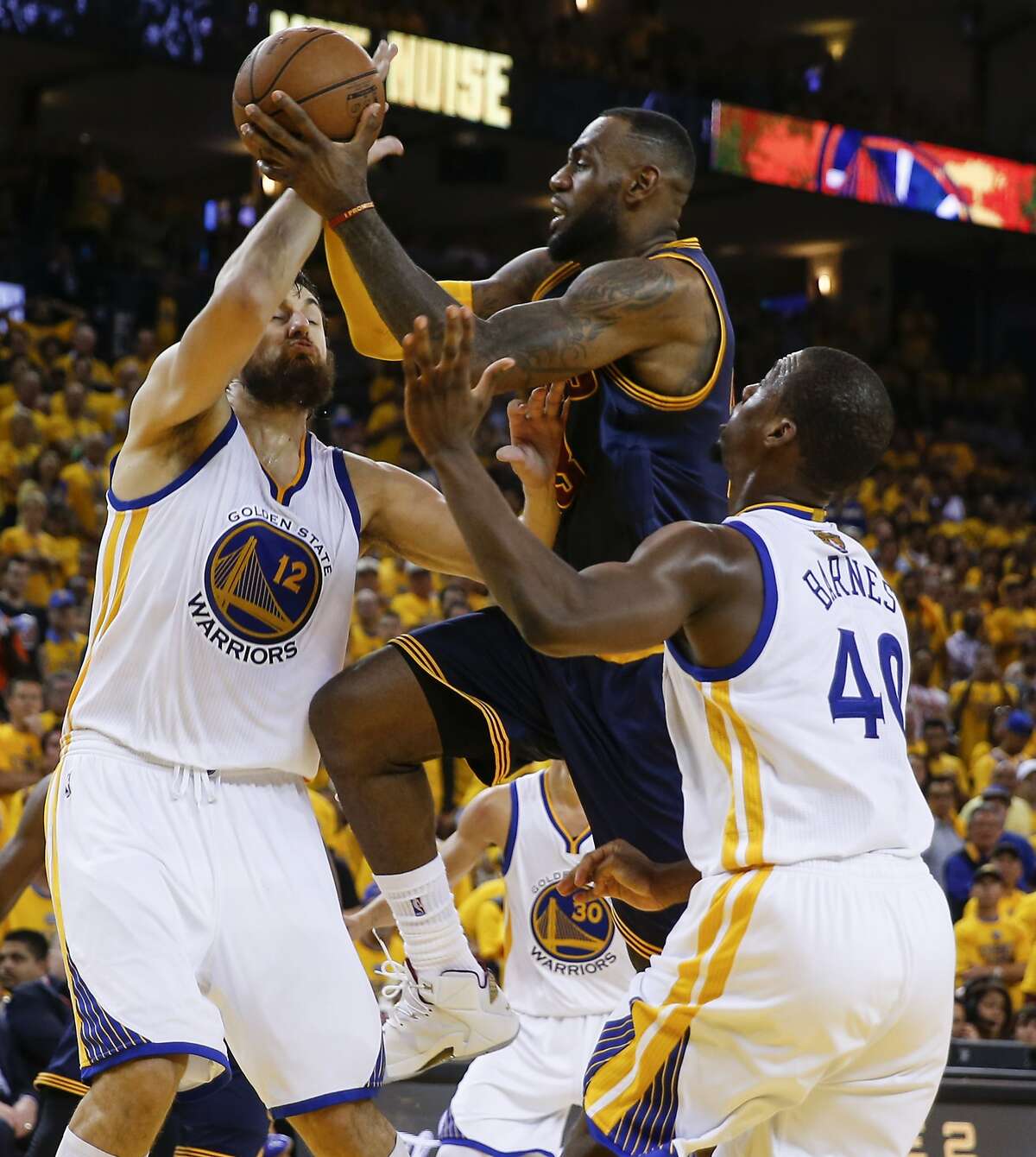 Cleveland Cavaliers' LeBron James tries to shoot between Golden State Warriors' Andrew Bogut and Harrison Barnes in the third period during Game 1 of The NBA Finals on Thursday, June 4, 2015 in Oakland, Calif.