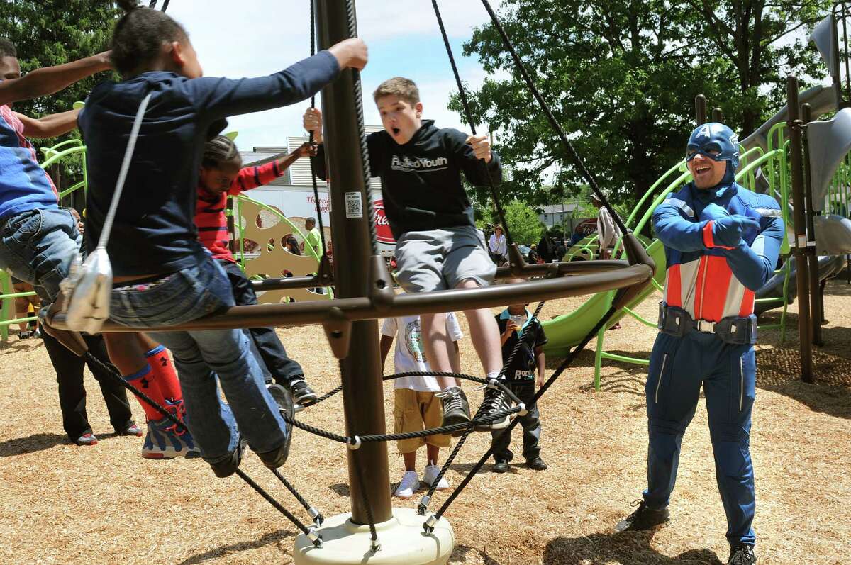 Capt. America, also known as Chad Baker, right, pushes children on a merry-go-round at the new Oak Street Park on Saturday, June 6, 2015, in Albany, N.Y. (Cindy Schultz / Times Union)