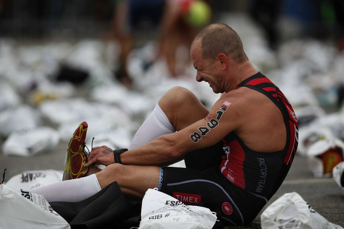 Kirk Lacko struggles to slip into his shoes during the transition to the bike portion of the "Escape from Alcatraz" triathlon in San Francisco, California, on Sunday, June 7, 2015.
