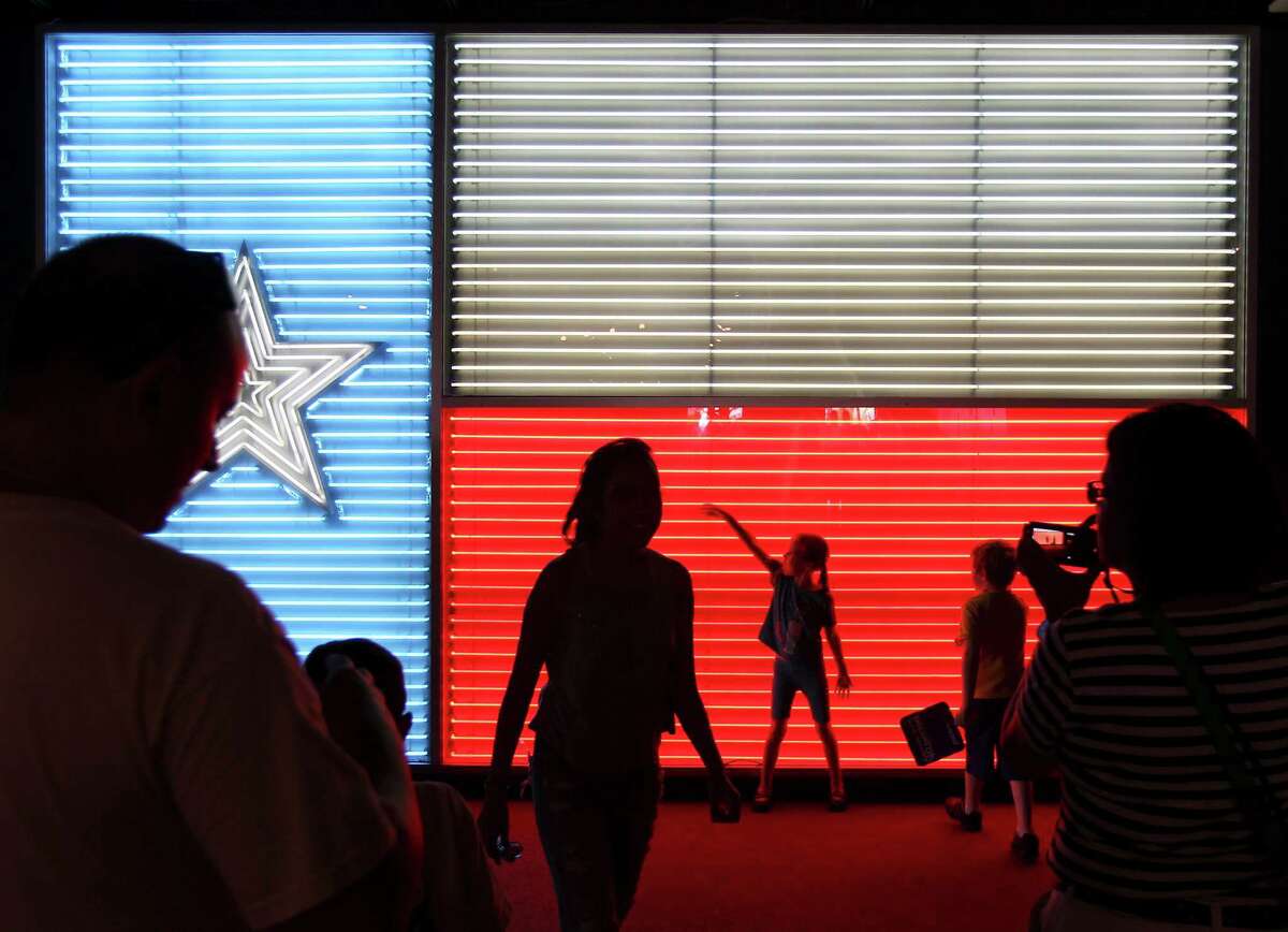 Guests walk past and pose at the popular neon Texas flag inside the Institute of Texan Cultures at the 2014 Texas Folklife Festival.