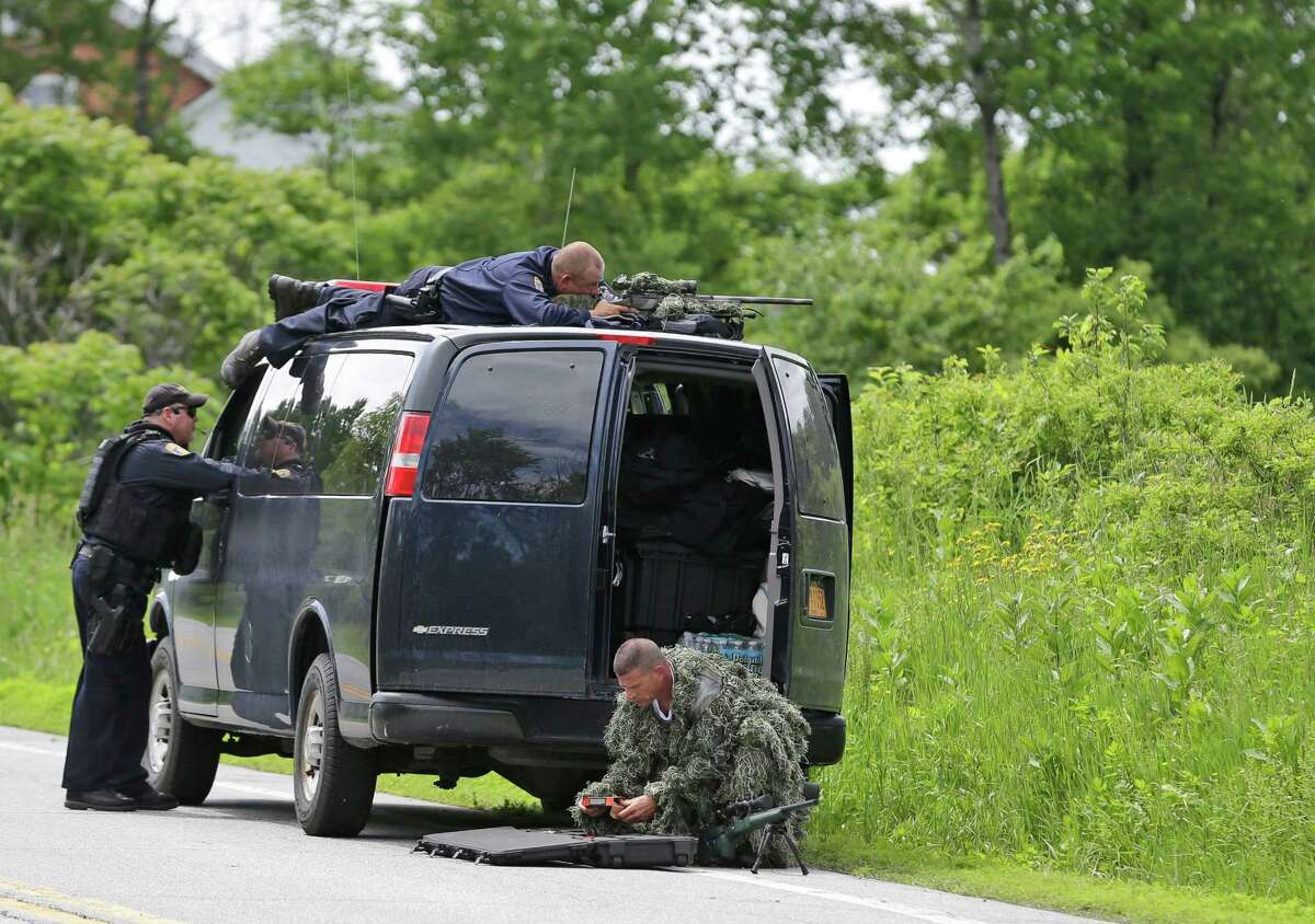 A law enforcement agent looks through a sniper scope while another in camouflage assembles a weapon during a search for two escaped killers in Boquet, N.Y., Tuesday, June 9, 2015. State and federal law officers are searching for David Sweat and Richard Matt, two killers who used power tools to break out of Clinton Correctional Facility in Dannnemora, close to the Canadian border. (AP Photo/Seth Wenig)