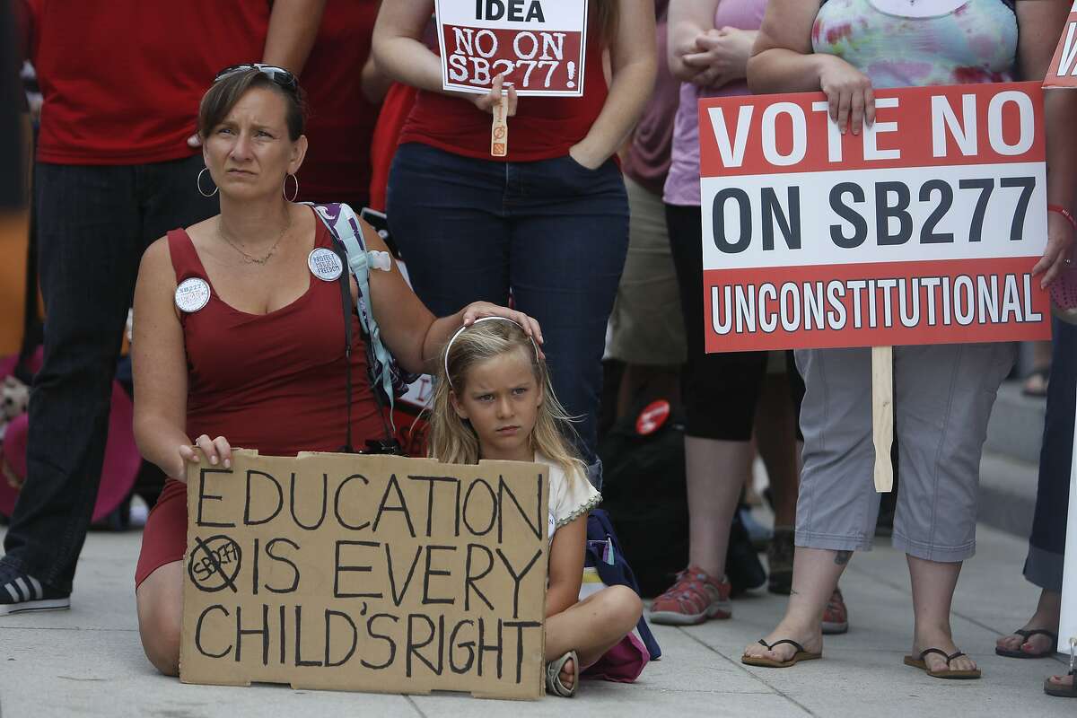 Michelle L'Don-Hayuk (l to r) sits with her daughter Sophia L'Don-Hayuk, 5, both of Brisbane, as they listen to speakers during a rally opposing SB 277 at the Capitol on Tuesday, June 9, 2015 in Sacramento, Calif.