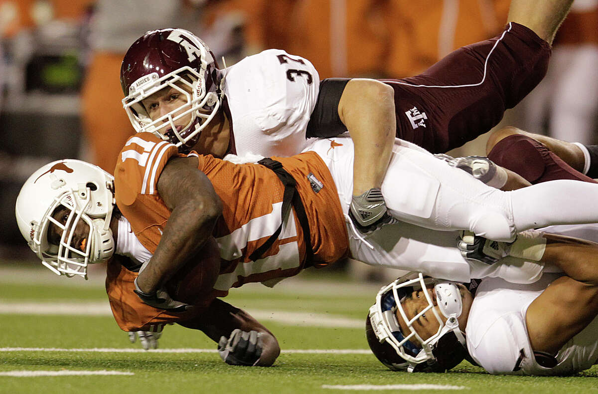 Texas wide receiver James Kirkendoll (11) is brought down by Texas A&M linebacker Michael Hodges (37) and cornerback Trent Hunter (1) during the first half on Nov. 25, 2010, in Ausitn.