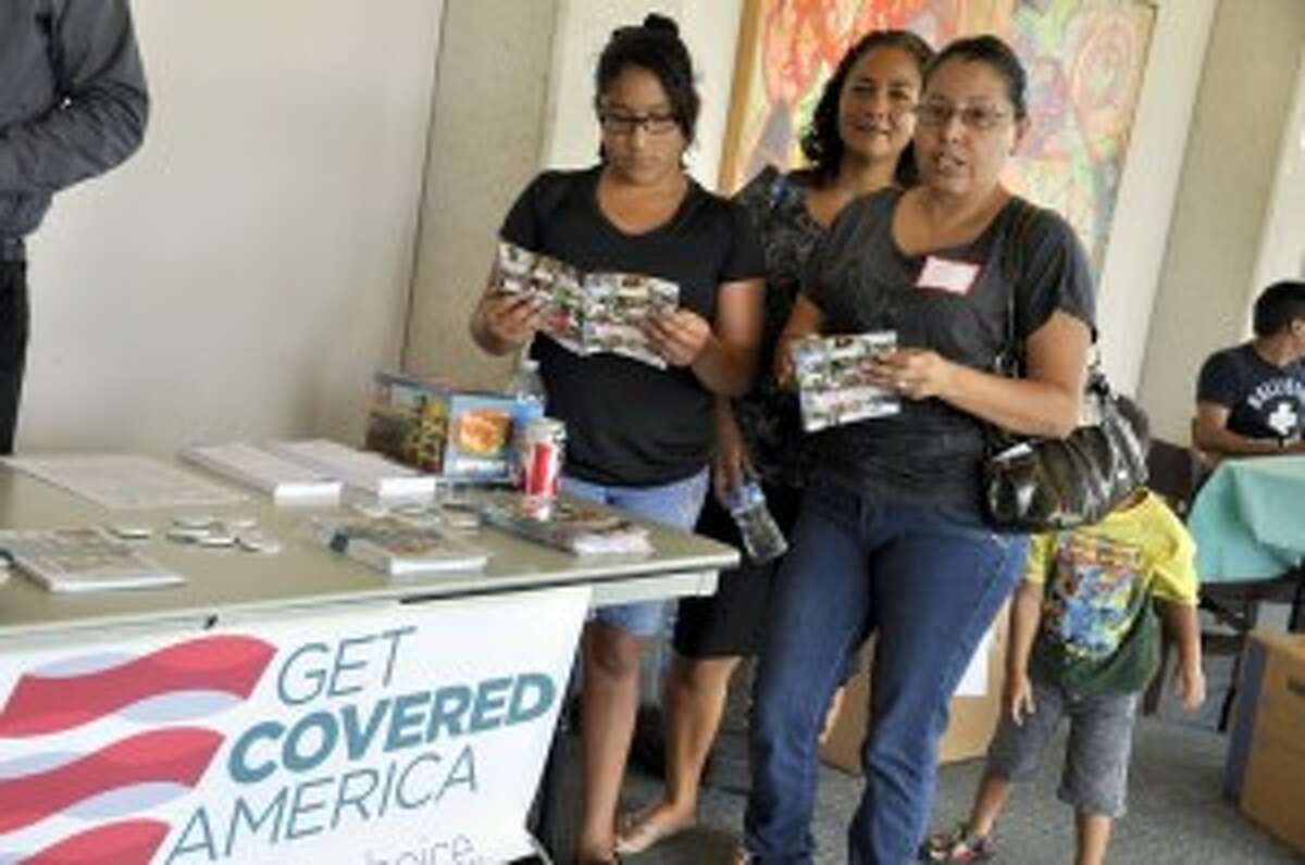 A family reviews Affordable Care Act insurance marketplace information at a health fair at the University of Houston during the 2014 enrollment. period.