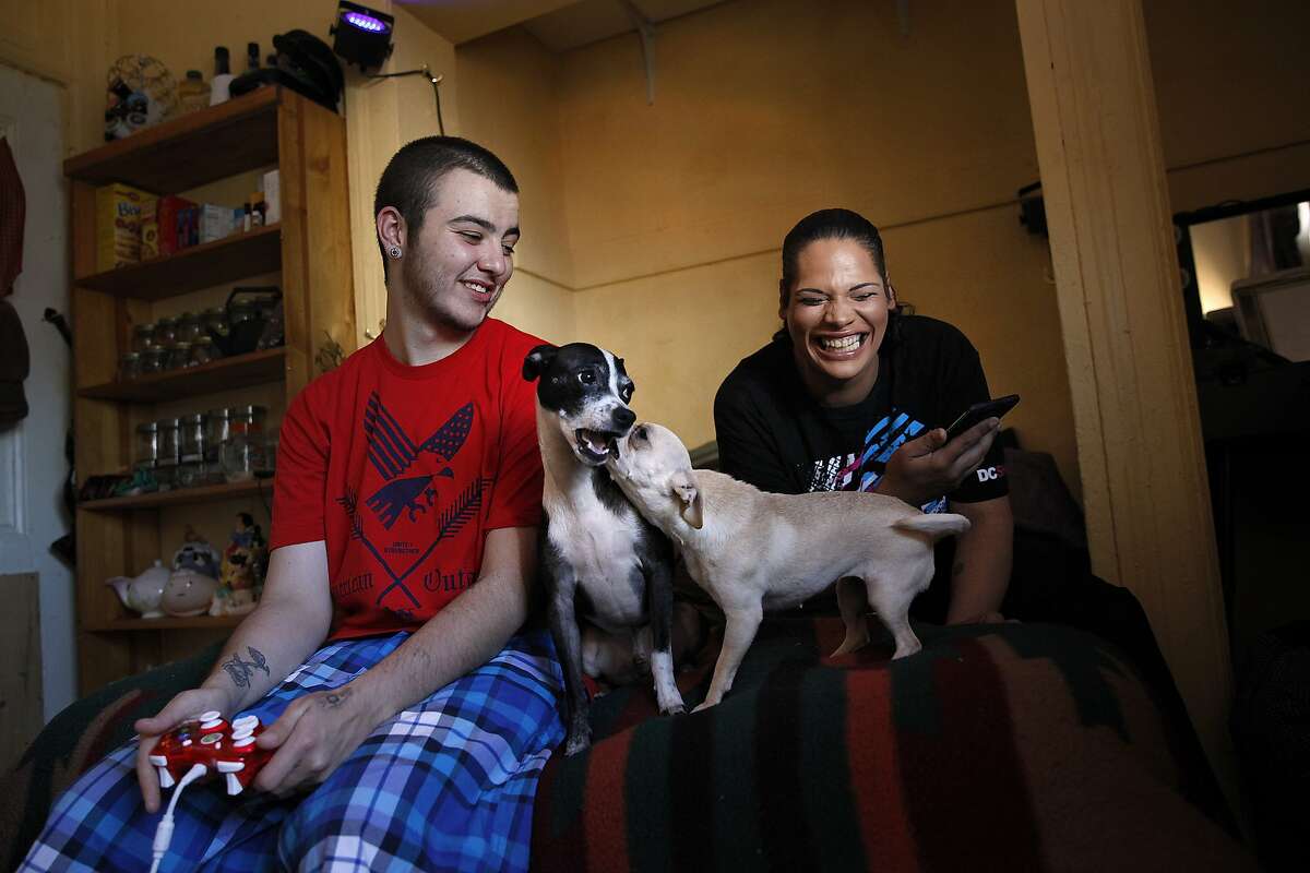 Trans couple Sadaisha Shimmers (right) and Jayson Dowker (left) play with their dogs in their new SRO located in the Tenderloin's Marathon Hotel in San Francisco, Calif., on Thursday, June 4, 2015. The trans couple became homeless when they had to flee their home for safety reasons. A new LGBT shelter is opening soon to help protect similar homeless youth from violence.