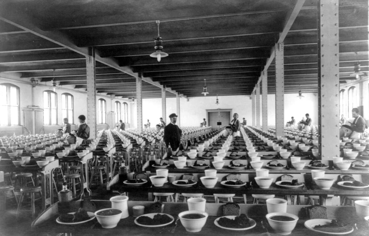 Photograph shows a Clinton Correctional Facility mess hall filled with several rows of set tables, 1912, in Dannemora, N.Y. (Library of Congress)