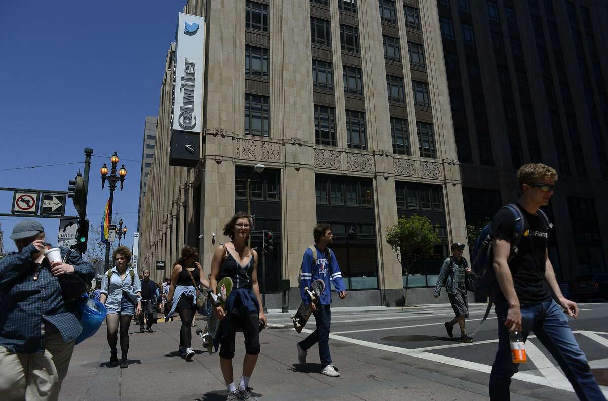 Pedestrians walk across 10th and Market Street in front of Twitter headquarters in San Francisco on June 11, 2015.