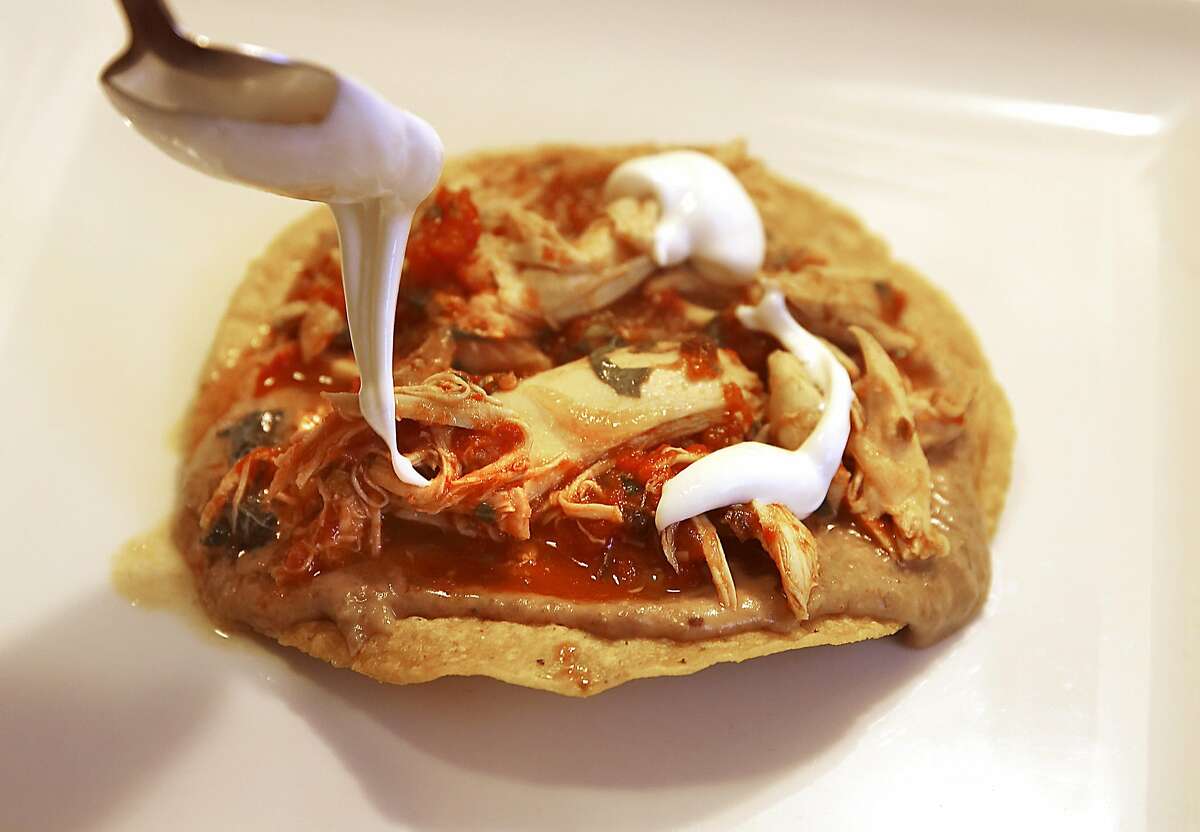 Chef Gonzalo Guzman drizzles a Chicken Tinga Tostada with kefir cream at his home in San Francisco.