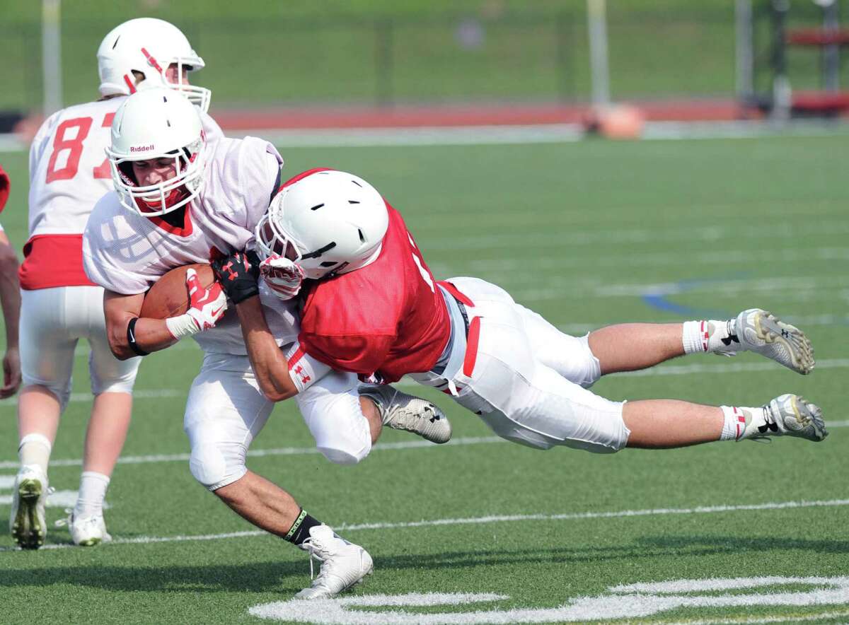 At left, white team receiver Anthony Ferraro, runs upfield after making a reception as red defender Joey Longo dives to make the tackle during the Red vs. White Greenwich High School football scrimmage at the school in Greenwich, Conn., Friday, June 12, 2015.