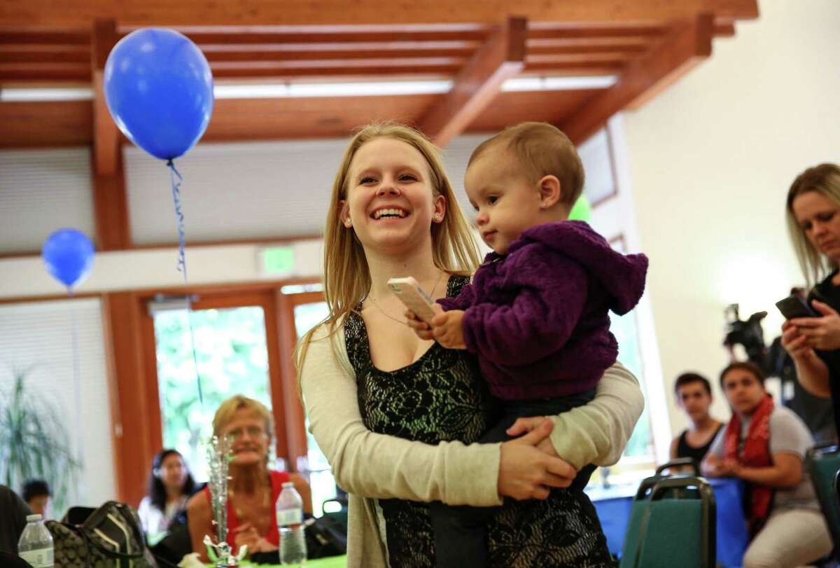 Brandy Hull, 18, a student at Puget Sound Skills Center, carries her daughter Lavayah, 1, as she stands to get an award during an event honoring students that completed a King County Truancy Program. Students that completed the program were honored by Prosecutor Dan Satterberg, former Sounders player Roger Levesque and former Seahawks player Paul Johns at the Tukwila Community Center on Friday, June 12, 2015.