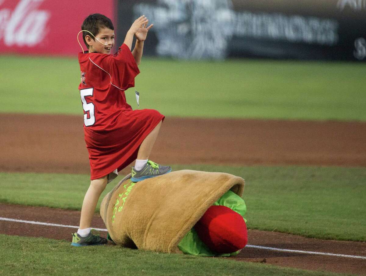 Zach Baza, 7, tackles the Puffy Taco during a Texas League baseball game between the Corpus Christi Hooks and the San Antonio Missions, Saturday, June 13, 2015, at Nelson Wolff Stadium in San Antonio. San Antonio won 4-1. (Darren Abate/For the Express-News)