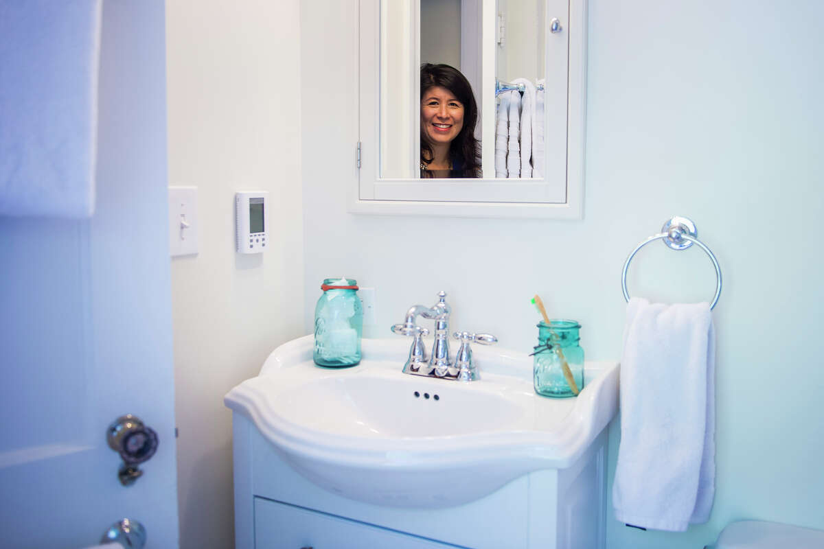 Although sticker shock kept Goo and her husband from renovating the bathroom earlier, "I love the new look," says Goo, pictured in the mirror. (MUST CREDIT: Washington Post photo by Jabin Botsford.)