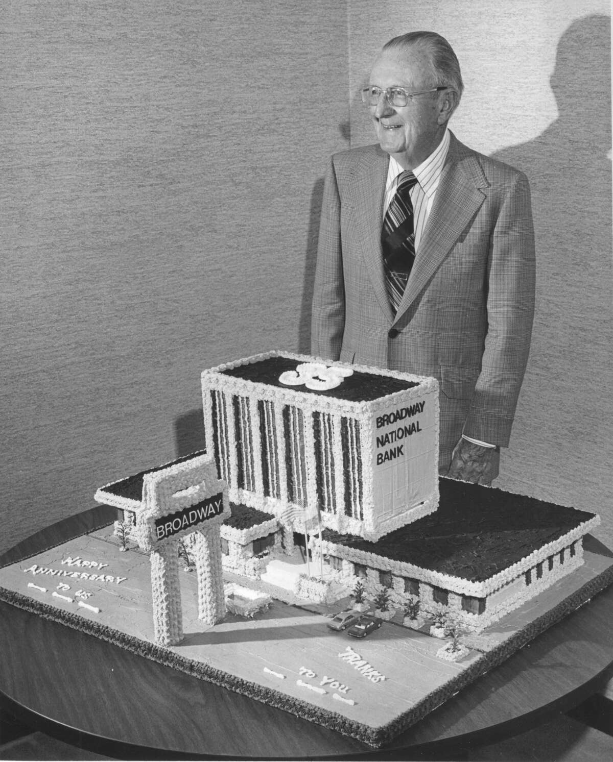 Col. C. E. Cheever poses near the bank-shaped cake for the Broadway National Bank's 35th anniversary in 1976.
